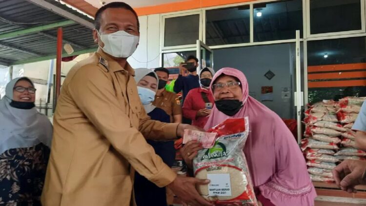 Wali Kota Pariaman, Sumbar, Genius Umar (kiri) menyalurkan bantuan dari pemerintah pusat berupa beras serta uang kepada warga terdampak PPKM dan sekaligus penerima manfaat PKH di Pariaman, Senin. (Antara)
