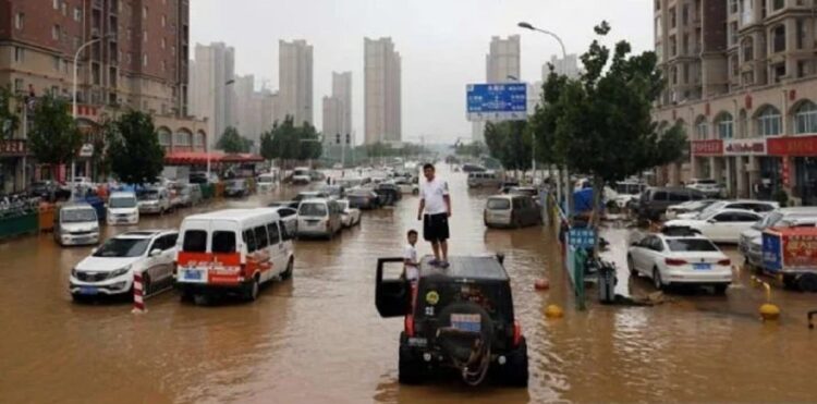 China Kembali Dilanda Banjir Besar, 80 Ribu Orang Mengungsi 1 Warga berada di atas mobilnya saat banjir yang merendam jalanan di Zhengzhou, Henan, China.