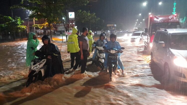 Personel polisi membantu warga yang terkena banjir pada Rabu malam.
