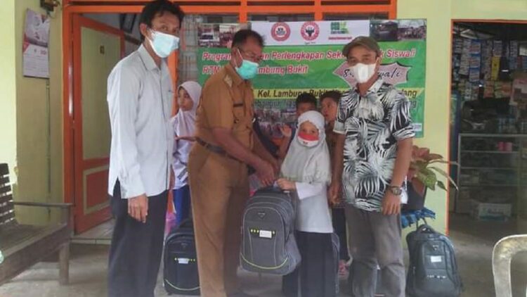 Lurah Lambung Bukit Yusrizal (dua dari kiri), menyerahkan bantuan paket pendidikan dari PT Semen Padang kepada salah satu pelajar dari RTM di Lambung Bukit.