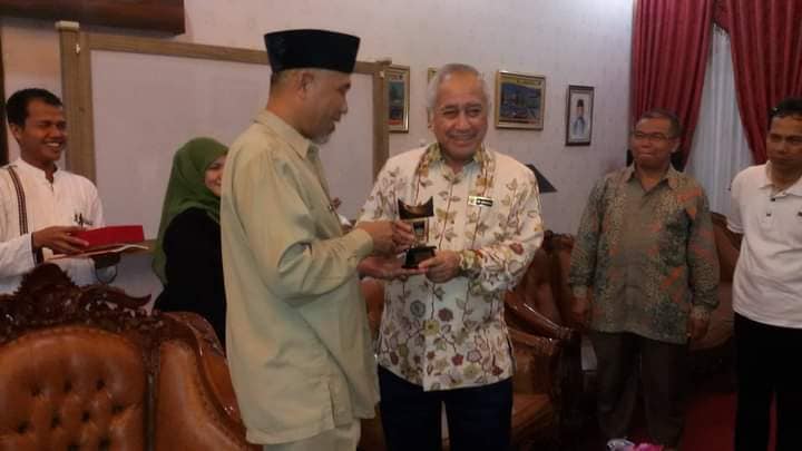 ES mendampingi Mahyeldi saat menyerahkan cendere mata.