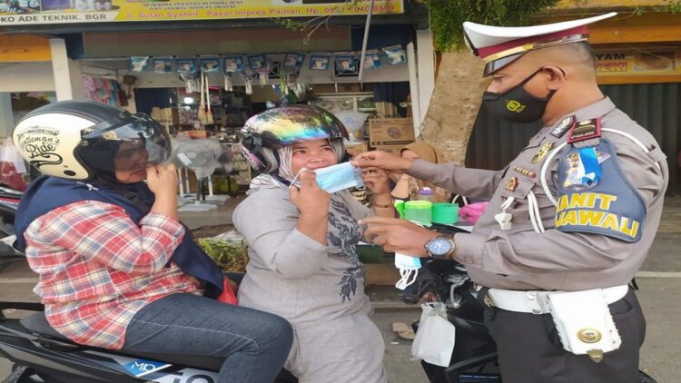 Aparat Satlantas Polres Pessel membagikan masker kepada pengendara yang kedapatan tidak memakai masker di sepanjang Jalan Raya Painan. (IST)