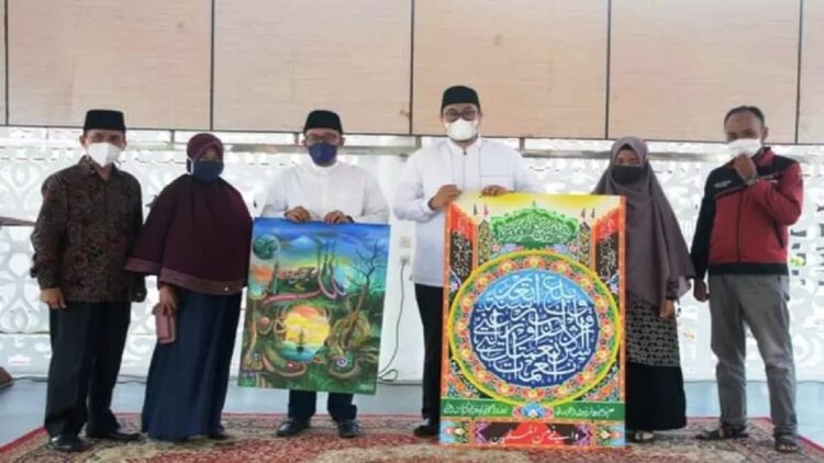 Bupati Tanah Datar Eka Putra (kiri) dan Wakil Bupati Richie Aprian memperlihatkan lukisan khaligrafi milik kafilah MTQ nasional tingkat Sumatera Barat. (Antara/Prokopim Setda Tanah Datar)
