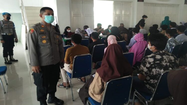 Terlihat Kapolsek Padang Timur AKP Afrides Roema memantau masyarakat dan pelajar mengikuti vaksin di gedung Adabiah Padang.