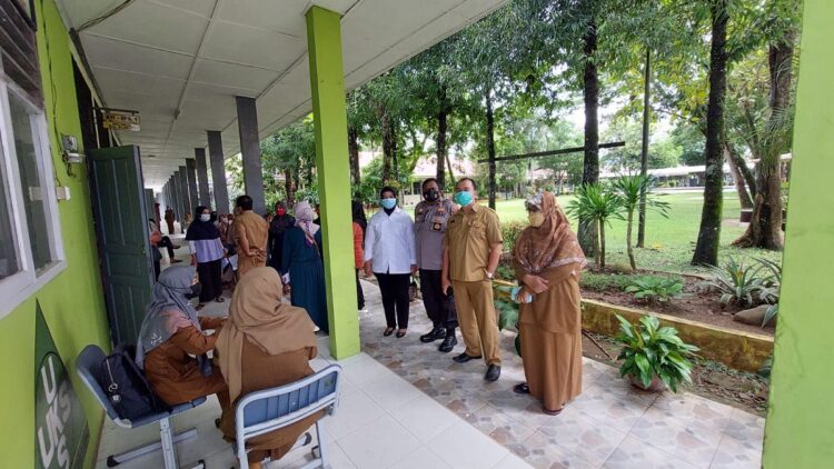 Terlihat Kasubag Humas Polresta Padang Ipda Adha Tawar didampingi kepala SMAN 12 Padang melihat proses vaksinasi. (IST)