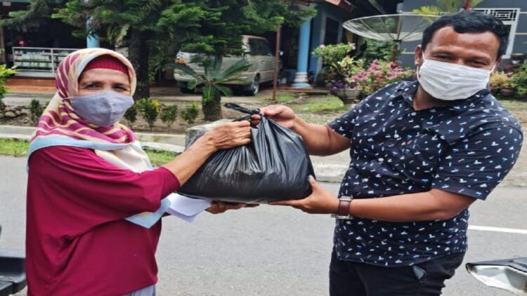 Kompol Jon Hendri membagikan sembako kepada warga usai divaksin. (IST)