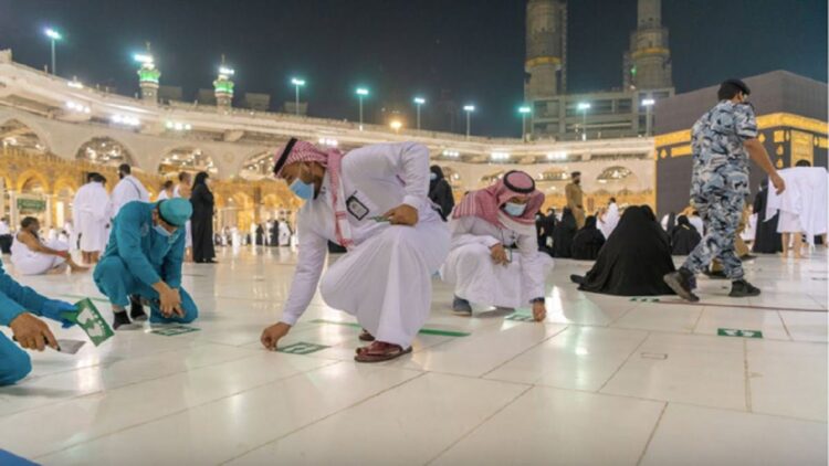 Arab Saudi Longgarkan Pembatasan, Salat Berjemaah di Masjidil Haram Digelar seperti Biasa 1 Petugas Masjidil Haram mencabut stiker jaga jarak menyusul pencabutan pembatasan kapasitas pada Minggu, 17 Oktober 2021. Foto: Dok. gph.gov.sa