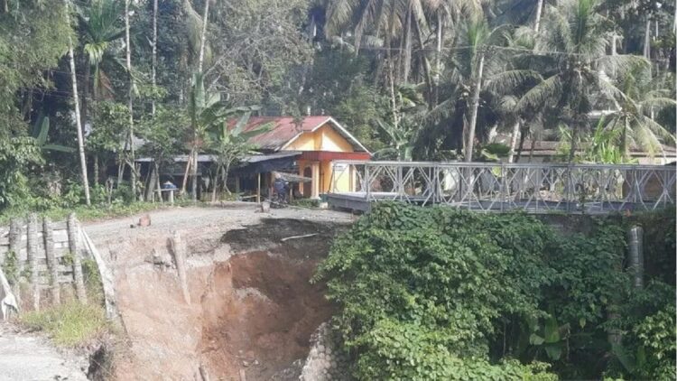 Jalan Padang Pariaman-Agam via Sungai Garinggiang Ditutup, Ada Pemasangan Jembatan Darurat 1 Salah seorang pengendara sepeda motor memasuki pekarangan rumah warga untuk menghindari proses perakitan jembatan darurat di Luhuang, Nagari Kuranji Hulu, Kecamatan Sungai Garinggiang, Padang Pariaman, Sumbar. (ANTARA/Aadiaat M.S)