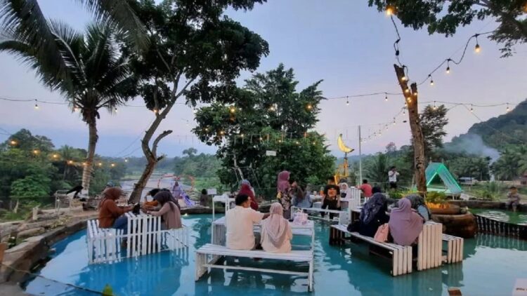 Wisatawan terlihat sedang menikmati makanan dan minuman di dalam kolam di objek wisata Tanjung Wahana Tano di Kecamatan VII Koto, Kabupaten Padang Pariaman, Sumbar dengan latar sungai, gunung, sawah, dan jembatan. (ANTARA/Aadiaat MS)