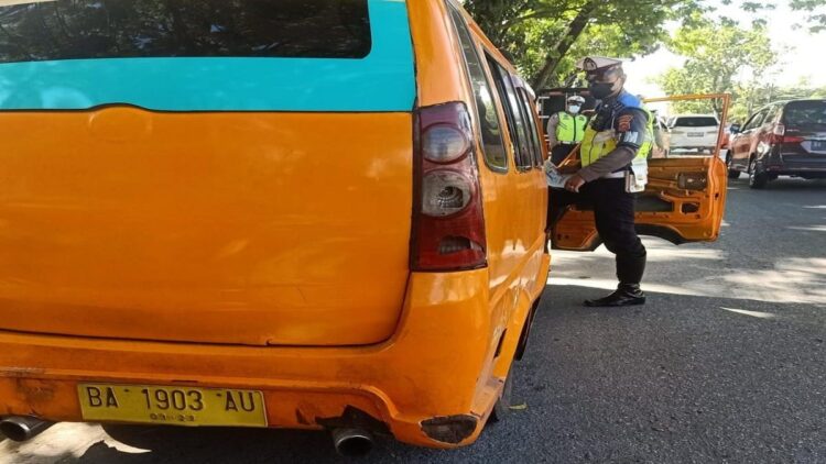 Terlihat personel Unit BM Satlantas Polresta Padang Aipda Rozi mencek bunyi knalpot angkot. (IST)