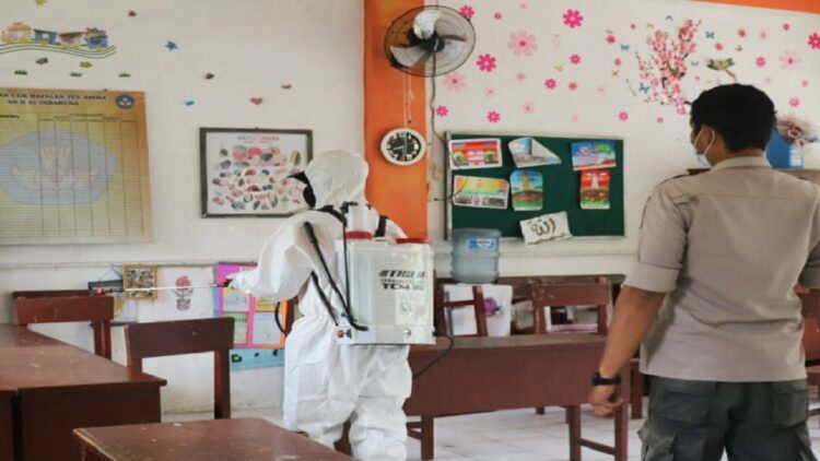 Petugas menyemprotkan cairan disinfektan di setiap ruang SDN 20 Indarung. (IST)