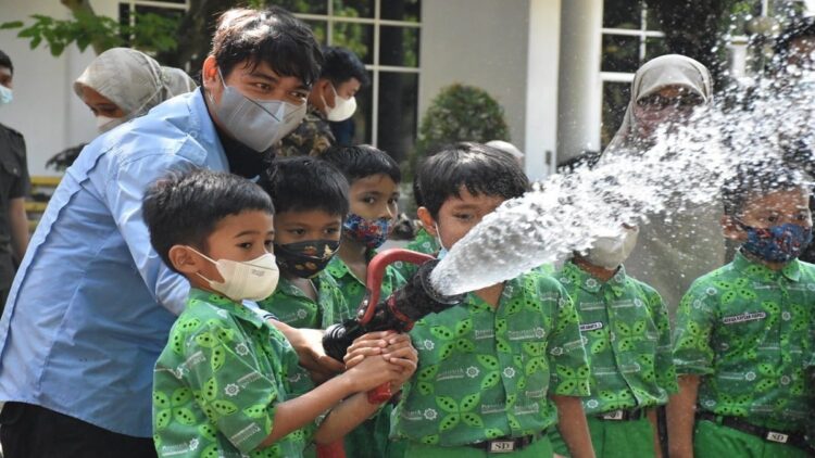 BPK Semen Padang Edukasi Siswa SD tentang Kebakaran dan Pengenalan Satwa Liar 1 Salah seorang petugas BPK PT Semen Padang mengajarkan teknik memadamkan api kepada siswa SD IT Permata Kita di area GSG, Senin (21/02/2022).