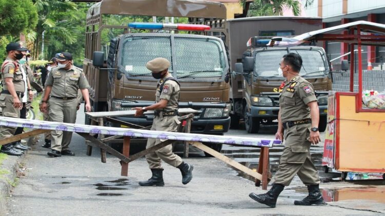 Anggota Satpol PP Kota Padang mengangkut material yang digunakan PKL berjualan di fasilitas umum. (IST)