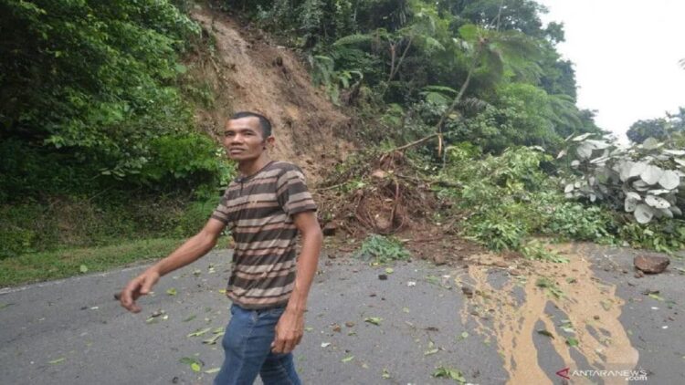 Ilustrasi - Warga melintas di depan material longsor, di jalan perlintasan Sumbar - Riau di Koto Alam, Kabupaten Limapuluhkota, Sumatera Barat, Minggu (9/5/2021). ANTARA FOTO/Iggoy el Fitra/foc.