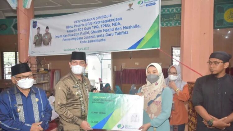 Wali Kota Sawahlunto Deri Asta menyerahkan secara simbolis kartu kepesertaan BPJS Ketenagakerjaan untuk guru mengaji, Kamis. (Antarasumbar/Yudha Ahada)