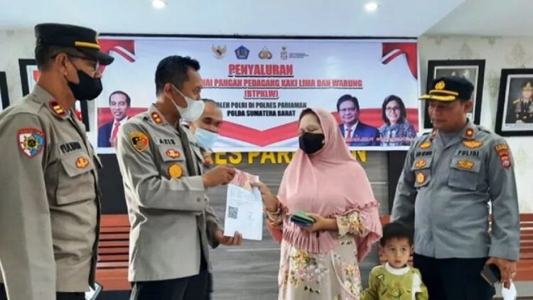 Kapolres Pariaman, Sumbar AKBP Abdul Azis (kiri) secara simbolis menyerahkan bantuan tunai pangan pedagang kaki lima dan warung kepada salah seorang penerima di Polres Pariaman, Rabu. (ANTARA/Aadiaat M.S.)