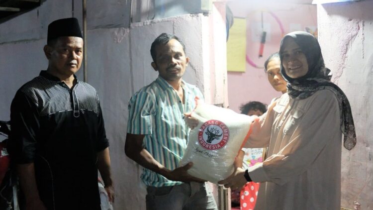 Staf Humas & Kesekretariatan PT semen Padang, Dina Armidya (kanan) didampingi Ketua RW 01 Ulak Karang Selatan, Muh Roiban, (kiri) menyerahkan bantuan sembako kepada Zulfikar, salah satu warga kurang mampu di Kampung Nelayan Transito pada acara Tok Tok Tok Buka Puasa Bersama PT Semen Padang, Kamis (21/4/2022).