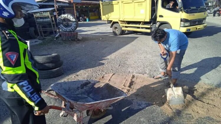 Polisi Satlantas Polres Bukittinggi timbun jalan rusak di Tanjuang Alam, Agam ( (Antara/Alfatah)