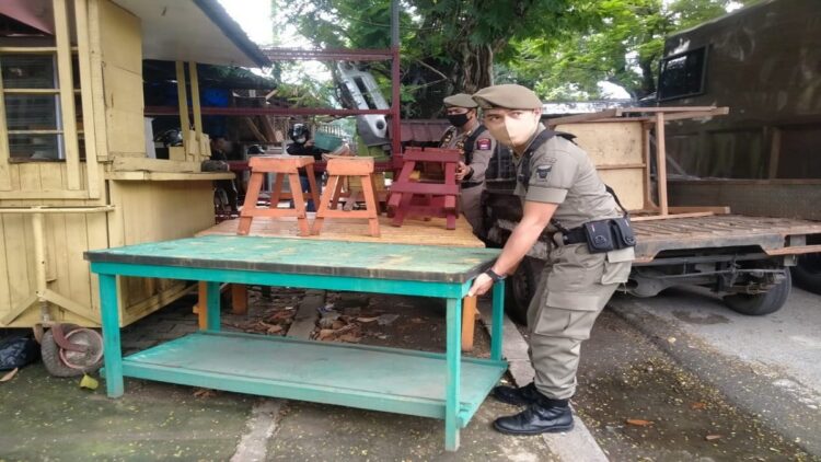 Satpol PP Padang mengangkut sejumlah peralatan yang digunakan PKL berdagang di trotoar. (IST)