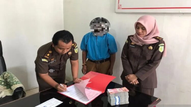 Kasi Pidsus Kejari Dharmasraya Afdal Putra (kiri) menandatangani berita acara penitipan uang kerugian negara dari tersangka FR, di Kejari Dharmasraya. (Antara/HO-Kejari Dharmasraya)