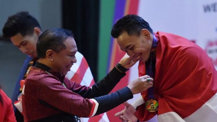 Menpora Zainudin Amali (kiri) mengalungkan medali emas kepada lifter Indonesia Eko Yuli Irawan (kanan) saat upacara penghormatan pemenang final angkat besi nomor 61 kg putra SEA Games 2021 Vietnam di Hanoi Sports Training and Competition Center, Hanoi, Vietnam, Jumat (20/5/2022). ANTARA FOTO/Zabur Karuru/nym.