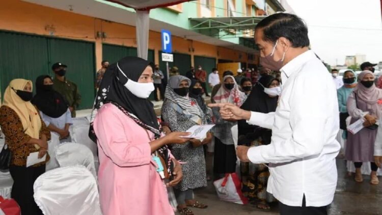 Presiden Joko Widodo menyerahkan BLT minyak goreng kepada penerima manfaat di Pasar Modern Angso Duo Jambi, Kamis (7/4/2022). BLT minyak goreng membantu mempertahankan daya beli masyarakat terhadap bahan pangan. (Antara/HO/Biro Pers Setpres)