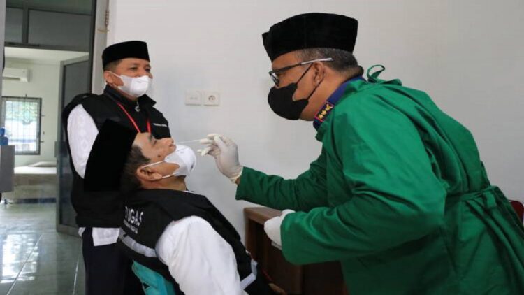 Sebelum Layani Jamaah, Seluruh PPIH Embarkasi Padang di-Swab Antigen 1 Salah seorang PPIH Embarkasi Padang yang juga Kakanwil Kemenag Sumbar Helmi melakukan swab antigen. (Humas Kemenag Sumbar)