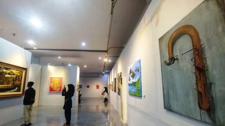 Pengunjung mengamati karya lukisan dalam pameran "Garih" yang diselenggarakan oleh para mahasiswa Seni Rupa Universitas Negeri Padang (UNP) dengan nama "Aliansi Generasi Micin" di Taman Budaya Sumbar, pada Senin (6/6). (ANTARA/Fathul Abdi)
