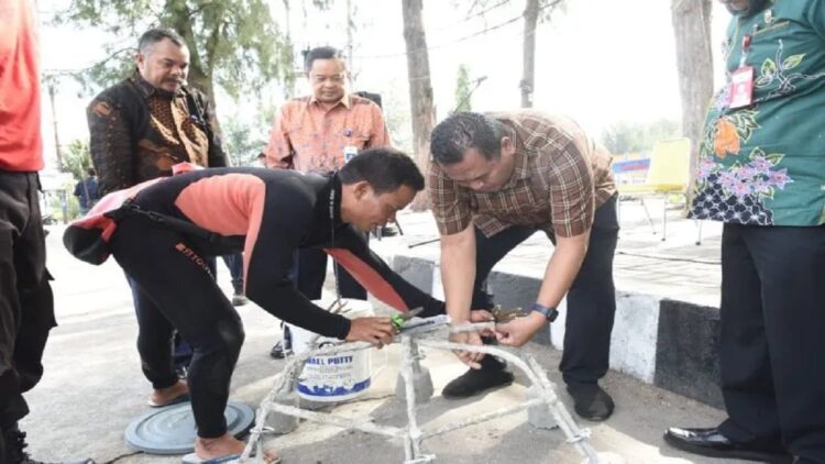 Sekretaris Daerah Kota Pariaman, Sumbar Yotta Balad (kanan) mengikat terumbu karang pada pelaksanaan pengabdian masyarakat oleh Poltekpel Sumbar di Kota Pariaman bertemakan tranplantasi terumbu karang kelompok masyarakat Pulau Angso Duo yang peluncurannya dilaksanakan Jumat (15/7/2022). (ANTARA/HO-Diskominfo Pariaman)