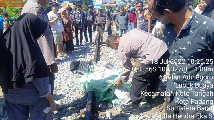 Petugas menutupi mayat korban usai terlindas kereta api. (IST)