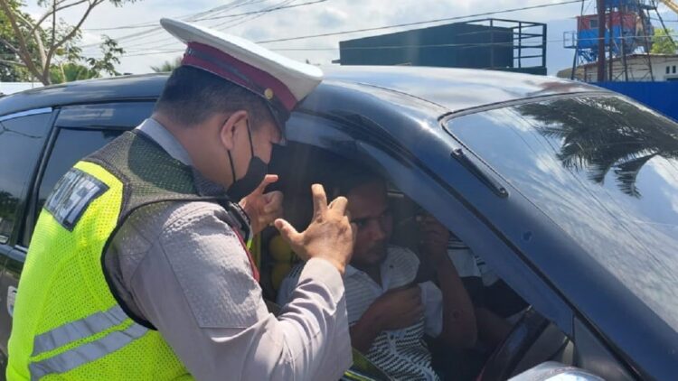 Personel Satlantas Polresta Padang mengingatkan pengendara memakai masker.