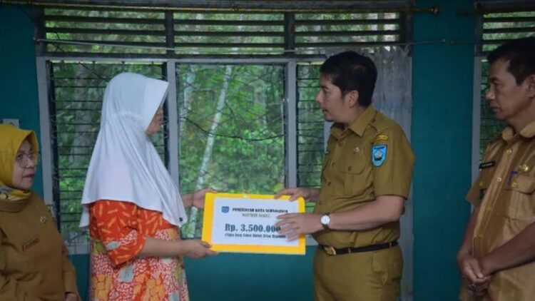Wali Kota Sawahlunto Deri Asta menyerahkan secara simbolis bantuan biaya pengobatan untuk warga, Selasa. (Antarasumbar/Yudha Ahada)