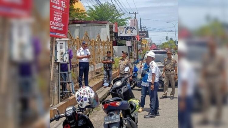 Tim gabungan memutus aliran listrik di Jalan Raya Lubukbegalung yang kerap digunakan PKL untuk berjualan. (IST)