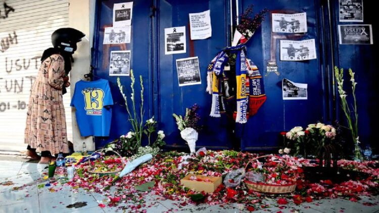 Seorang ibu mengintip dari sela-sela pintu pasca tragedi yang terjadi pada pekan ke-11 Liga 1 2022-2023 seusai pertandingan bertajuk Derbi Jawa Timur, Arema FC melawan Persebaya Surabaya di Stadion Kanjuruhan Kepanjen, Kabupaten Malang, Senin (3/10/2022) siang. (KOMPAS.com/SUCI RAHAYU)