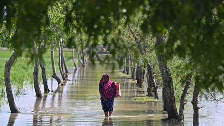 Seorang perempuan berjalan menerobos banjir setelah Topan Sitrang melanda Bangladesh pada Senin (24/10/2022) malam. (Foto : AFP/Munir UZ ZAMAN)
