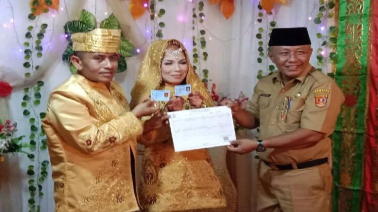 Kepala Dinas Kependudukan dan Pencatatan Sipil Agam, Helton menyetahkan KTP dan KK kepada pengantin. (Antara/Yusrizal)