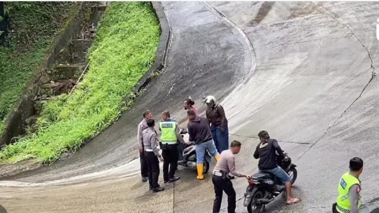 Personel Ditlantas Polda Sumbar membantu pengendara yang terjatuh akibat tumpahan CPO di Sitinjau Lauik. (Istimewa)