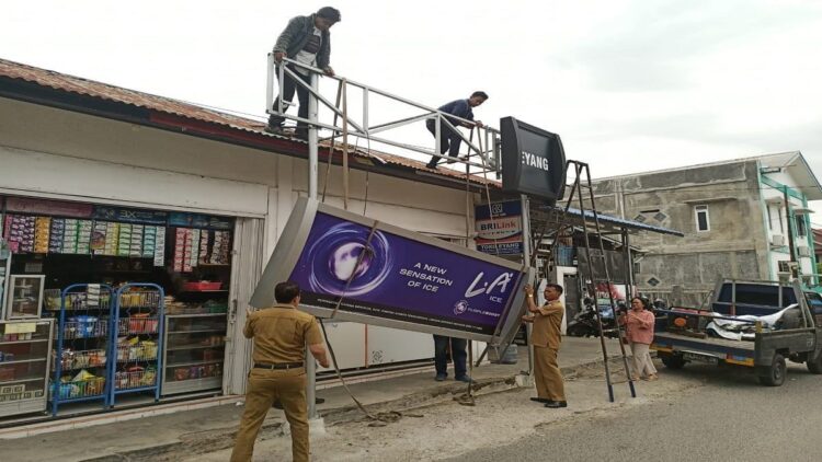 Petugas Bapenda Kota Padang membongkar sejumlah reklame yang belum membayar pajak. (radarsumbar.com/infopublik.id)