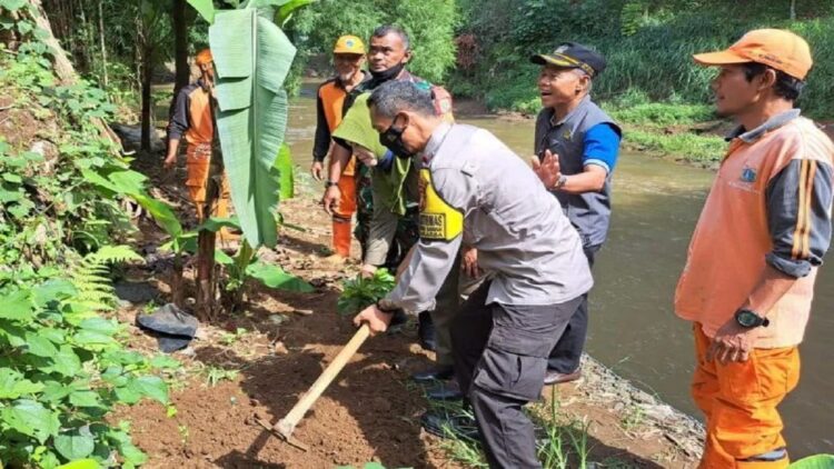 Bhabinkamtibmas Kelurahan Srengseng Sawah membantu warga menanam bibit pohon alpukat Cipedak di bantaran Sungai Ciliwung, Jakarta, Rabu (14/12/2022). ANTARA/HO-Polsek Jagakarsa