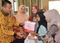 Wali Kota Pariaman Genius Umar (kiri) secara simbolis memberikan bantuan makanan, susu, dan biskuit kepada keluarga anak berisiko stunting saat peluncuran Bapak Asuh Anak Stunting di Pariaman. (ANTARA/HO-Diskominfo Pariaman)