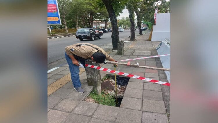 Petugas mencek lubang trotoar yang berada di depan Tugu Gempa Padang. (Foto: Dok. Istimewa)