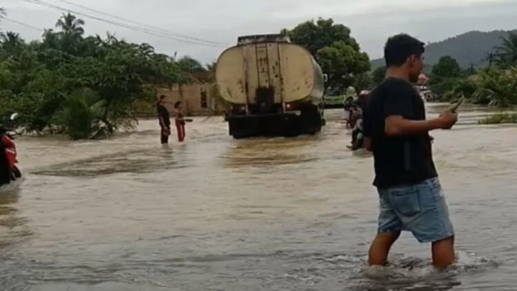 Warga sedang melewati banjir menggenangi jalan nasional di Muaro Kandang, Kecamatan Palemayan, Kabupaten Agam. Dok Rano Fajri