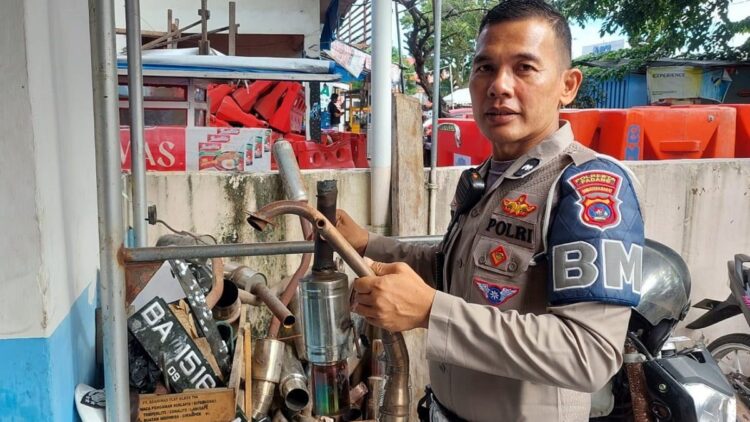Pakai Knalpot Racing, Kendaraan Roda Dua Didenda Rp250 Ribu 1 Personil Unit BM Satlantas Polresta Padang memperlihatkan knalpot racing yang diamankan dari pelanggar lalu lintas di Padang. (Dok. Istimewa)