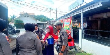 Petugas mengamankan perempuan pengemis yang menggendong bayi di jalan raya. (Foto: Dok. Satpol PP Kota Padang)