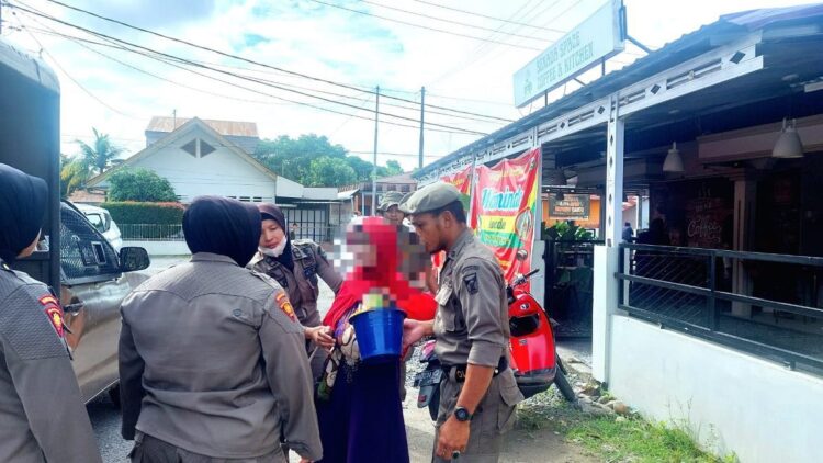Petugas mengamankan perempuan pengemis yang menggendong bayi di jalan raya. (Foto: Dok. Satpol PP Kota Padang)