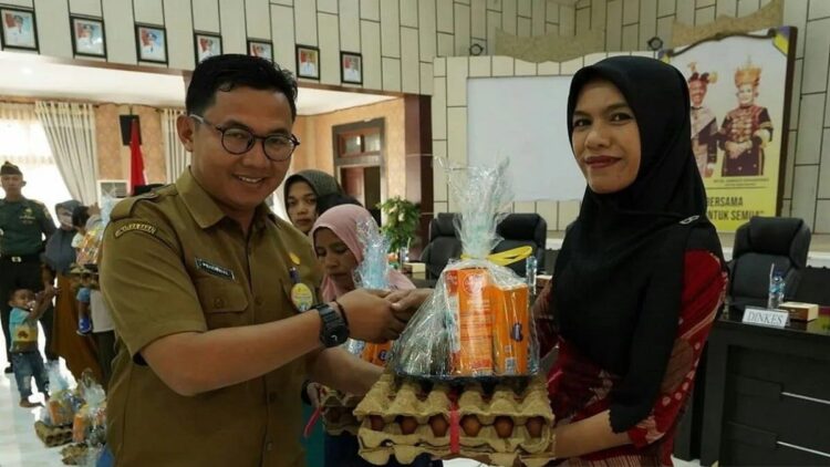 Kepala Dinas Kesehatan Solok Selatan Pendewal menyerahkan bahan makanan bergizi dan susu bagi Balita guna percepatan penanggulangan stunting kepada seorang ibu rumah tangga. Antara/Erik