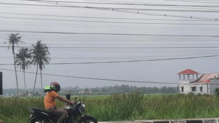 Seorang pengendara melintas di jalan raya di Pariaman, Sumbar, dengan latar kabut asap terlihat dari kejauhan. (Antara/Aadiaat MS)