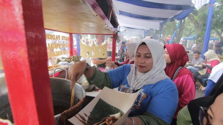 Salah seorang pedagang sate menyiapkan pesanan pembeli yang menggunakan metode pembayaran digital (QRIS), di Padang, Sumbar, Minggu (22/10/2023). ANTARA/Fandi Yogari