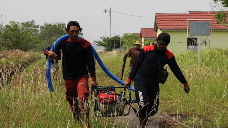Petugas satgas gabungan kebakaran hutan dan lahan (karhutla) mengangkat mesin pompa air untuk memadamkan api yang membakar lahan di dekat permukiman di Kelurahan Sabaru, Palangka Raya, Kalimantan Tengah, Senin (2/10/2023). (ANTARA FOTO/Auliya Rahman/hp).