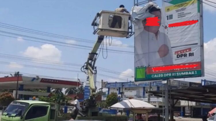 Petugas menurunkan alat peraga sosialisasi yang menyerupai alat peraga kampanye di Jalan Lintas Sumatera, Rabu (15/11). (Foto: Antara)